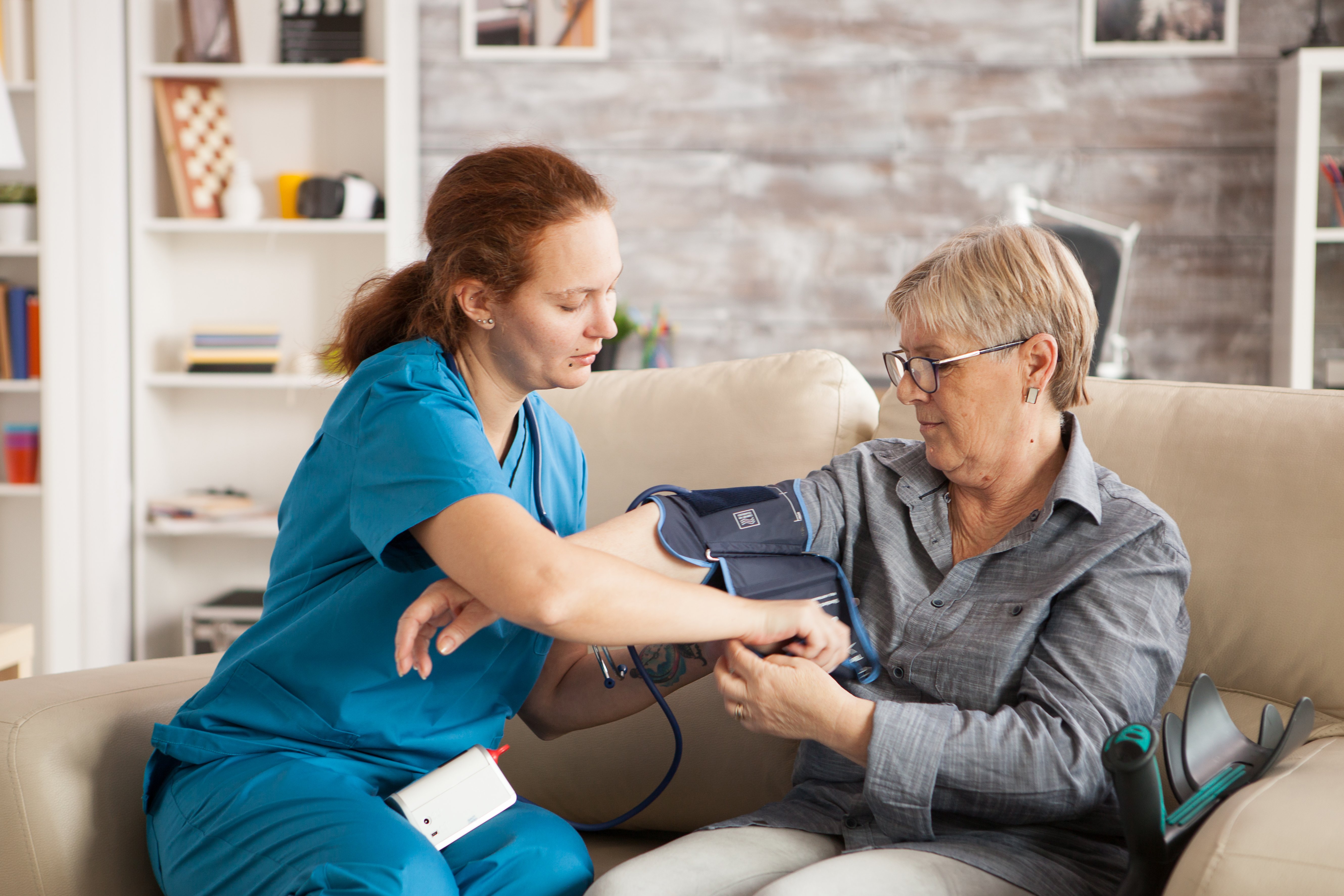 female-nurse-using-digital-blood-pressure-device-senior-woman-nursing-home