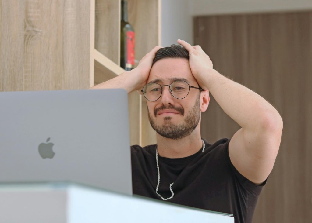 Man pulling his hair in frustration looking at his computer